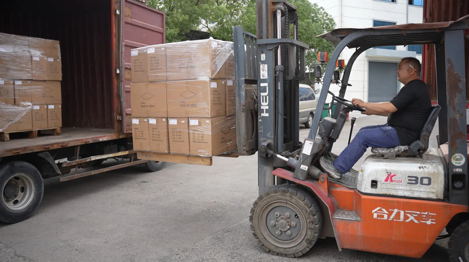 Forklift loading palletized export cartons into a shipping container